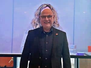 Johan Sponselee met kapsel deelneemster op de achtergrond.